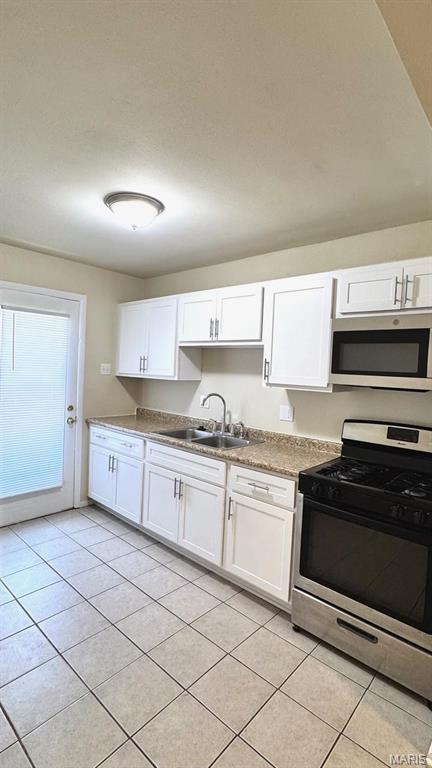 4028 Esseldale Dr, Saint Ann, MO 63074 - kitchen featuring stainless steel appliances, a sink, light tile patterned floors, and white cabinetry