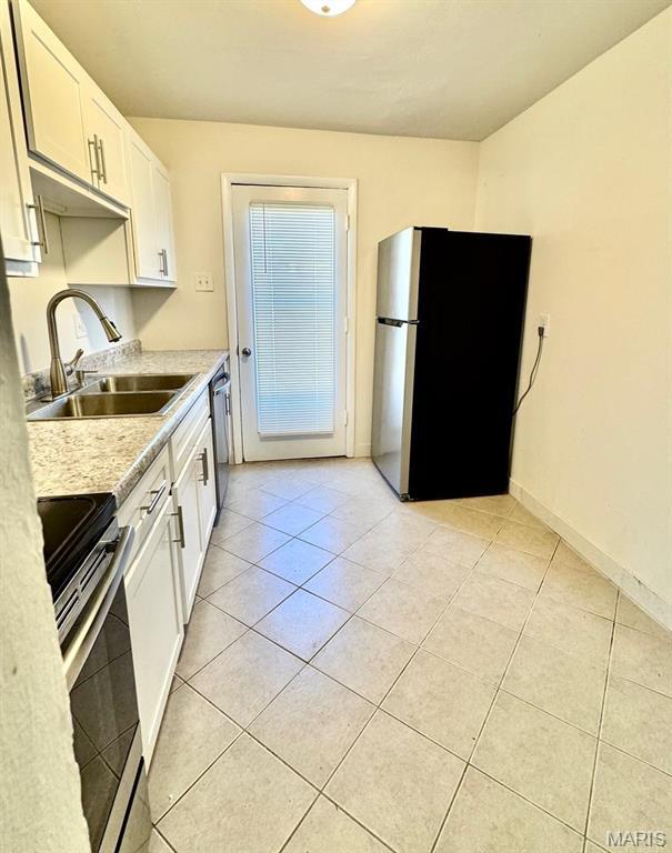4028 Esseldale Dr, Saint Ann, MO 63074 - kitchen with appliances with stainless steel finishes, a sink, light countertops, light tile patterned floors, and white cabinets