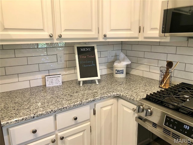 1215 Brookstone Ln, Lake St Louis, MO 63367 - kitchen featuring stainless steel appliances, white cabinets, tasteful backsplash, and light stone countertops