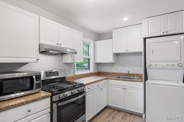 284 Ramsey Ln, Ballwin, MO 63021 - kitchen with appliances with stainless steel finishes, under cabinet range hood, a sink, stacked washer / drying machine, and light wood-style flooring