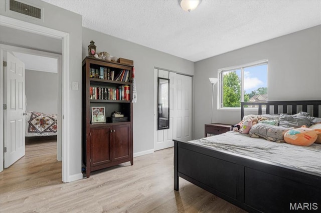 284 Ramsey Ln, Ballwin, MO 63021 - bedroom with light wood-style floors, a textured ceiling, a closet, and baseboards