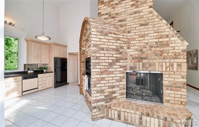14424 Valley Meadow Ct W, Chesterfield, MO 63017 - kitchen featuring freestanding refrigerator, cream cabinets, a fireplace, dark countertops, and a towering ceiling