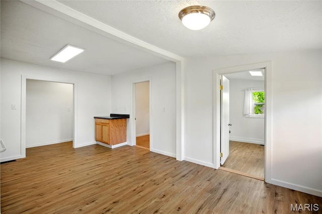 402 N 11th St, De Soto, MO 63020 - unfurnished room featuring light wood-style flooring, baseboards, and a textured ceiling