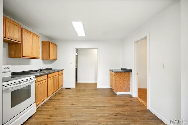 402 N 11th St, De Soto, MO 63020 - kitchen with white electric stove, light wood finished floors, dark countertops, and baseboards