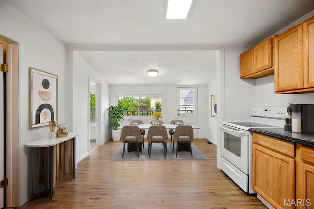 402 N 11th St, De Soto, MO 63020 - kitchen featuring white electric range oven, light wood-style floors, dark countertops, and baseboards
