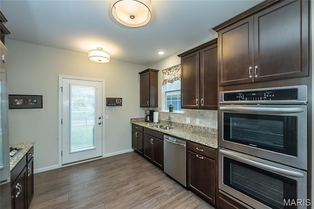 17006 Main St, Wildwood, MO 63040 - kitchen featuring appliances with stainless steel finishes, a sink, dark brown cabinets, wood finished floors, and baseboards