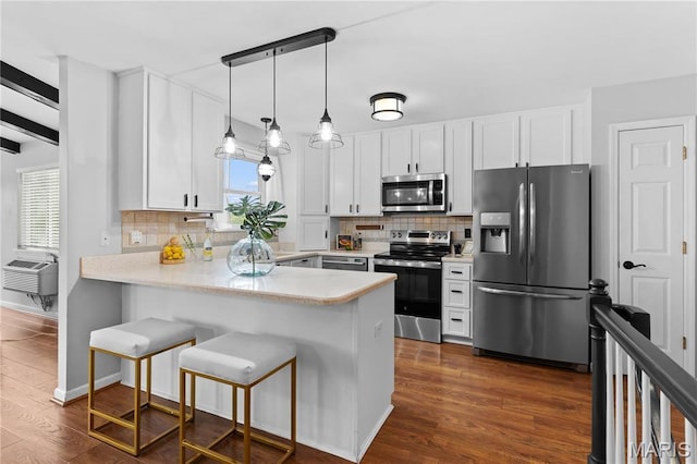 827 Bridgewater Xing, Villa Ridge, MO 63089 - kitchen with appliances with stainless steel finishes, a peninsula, dark wood-style floors, white cabinets, and tasteful backsplash