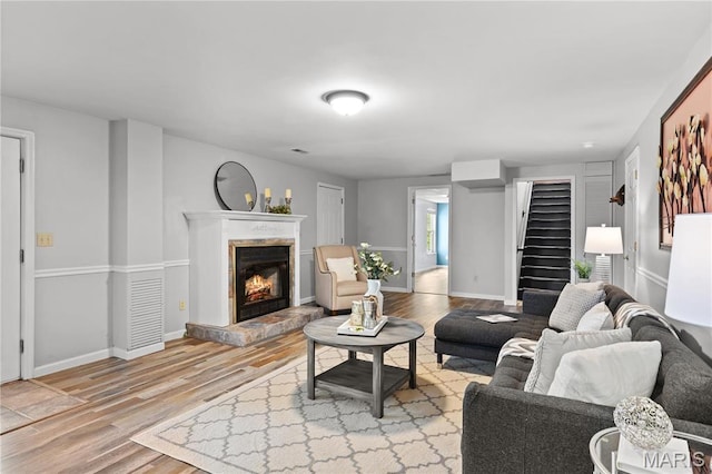 827 Bridgewater Xing, Villa Ridge, MO 63089 - living room with light wood-style flooring, stairway, a tile fireplace, and baseboards