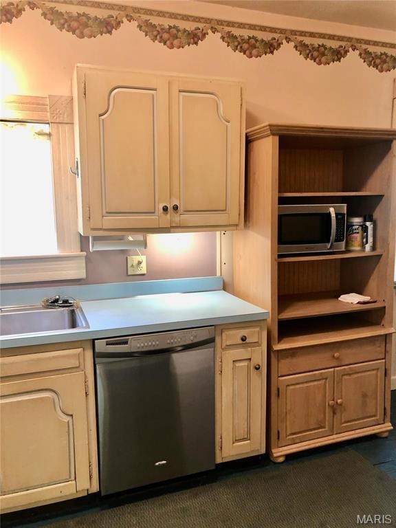 kitchen with appliances with stainless steel finishes, a sink, and light countertops