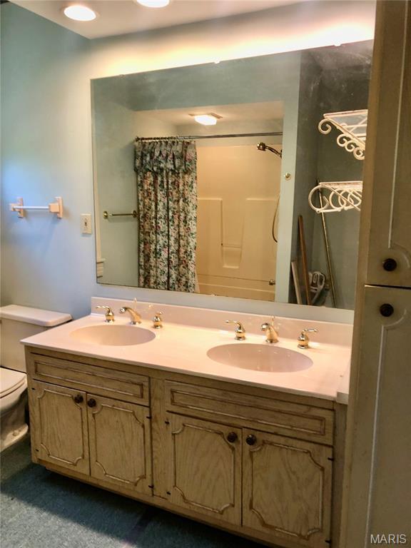 bathroom with a shower with shower curtain, toilet, and double vanity