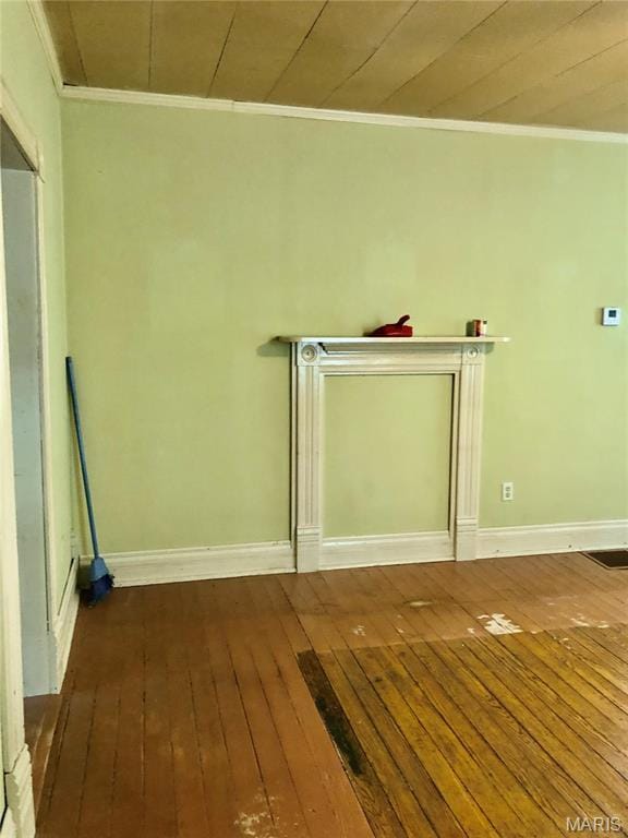 empty room with hardwood / wood-style floors, ornamental molding, and baseboards