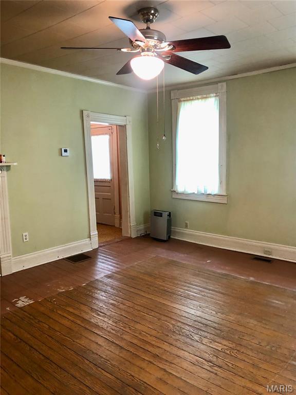 unfurnished room featuring ceiling fan, wood-type flooring, ornamental molding, and baseboards