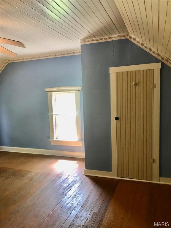 additional living space featuring vaulted ceiling, hardwood / wood-style floors, wooden ceiling, a ceiling fan, and baseboards