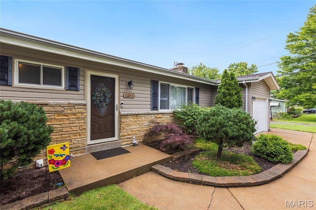 1261 Whispering Winds Dr, Arnold, MO 63010 - view of exterior entry featuring stone siding, a chimney, and a garage