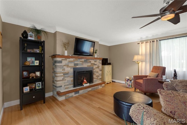 1261 Whispering Winds Dr, Arnold, MO 63010 - living area with light wood finished floors, a stone fireplace, and ceiling fan