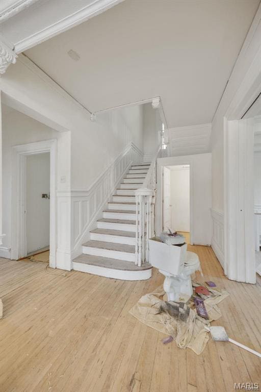 foyer with stairway, a decorative wall, hardwood / wood-style floors, and a wainscoted wall