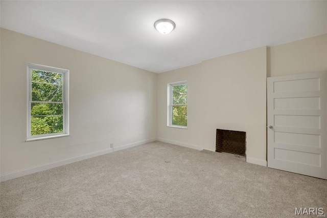 unfurnished living room featuring plenty of natural light, carpet, and baseboards