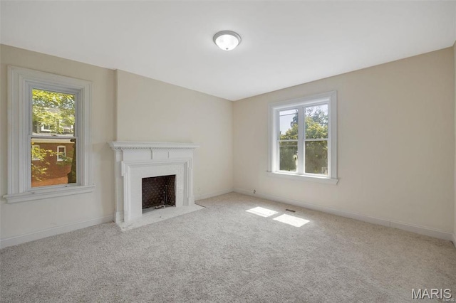 unfurnished living room featuring plenty of natural light, carpet flooring, a fireplace with flush hearth, and baseboards