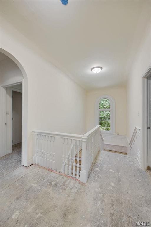 corridor featuring an upstairs landing and arched walkways