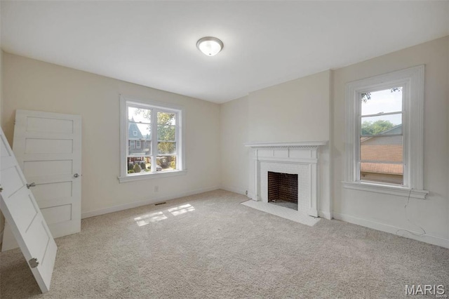 unfurnished living room with carpet floors, a brick fireplace, and baseboards