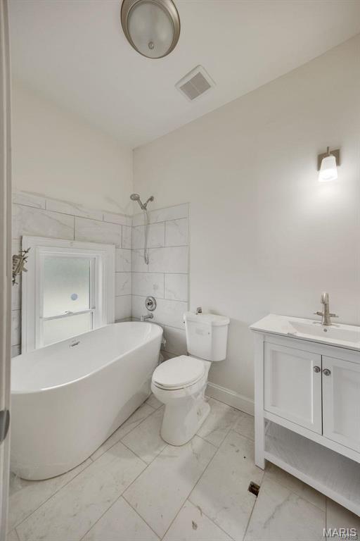 bathroom featuring marble finish floors, toilet, a soaking tub, a shower, and vanity