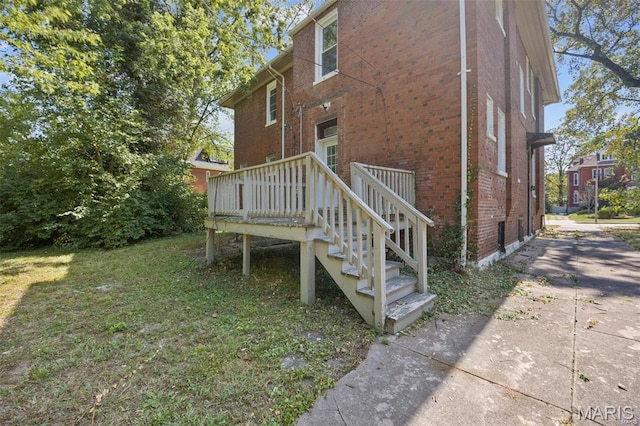 rear view of property featuring brick siding, a deck, and stairs