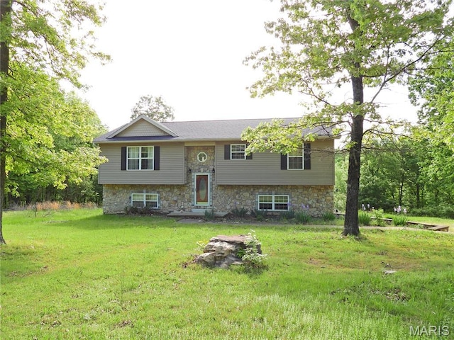 split foyer home featuring a front yard and stone siding