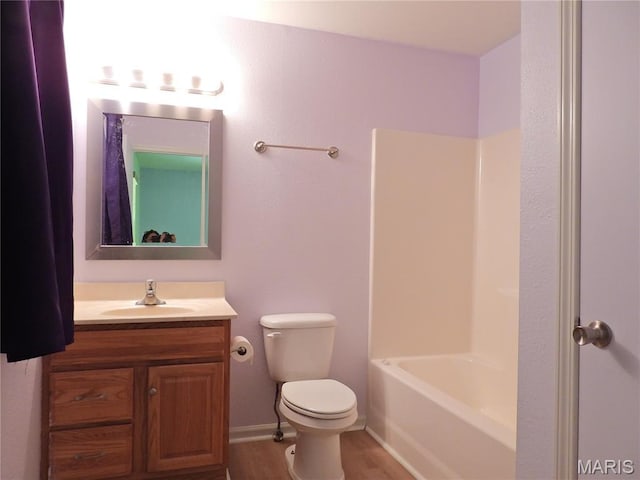 bathroom with vanity, toilet, wood finished floors, shower / tub combination, and baseboards