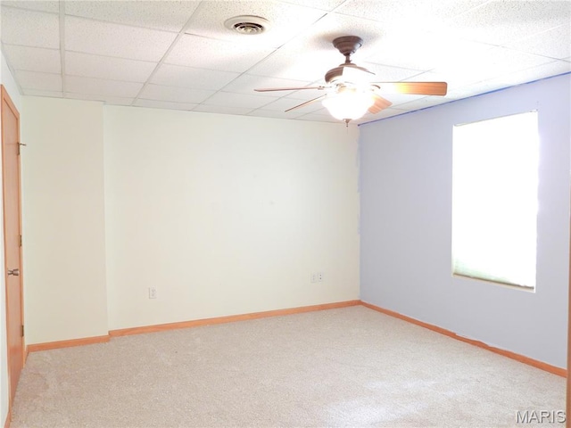 empty room with a ceiling fan, a drop ceiling, light carpet, and baseboards