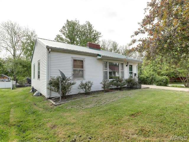 view of front of house with a chimney, a front lawn, and metal roof