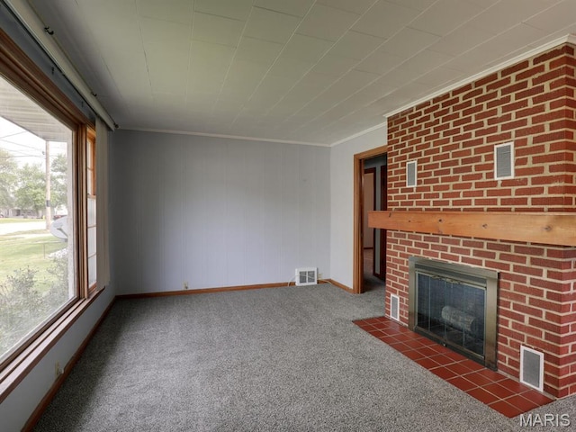 unfurnished living room with crown molding, plenty of natural light, carpet flooring, a brick fireplace, and baseboards