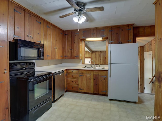kitchen featuring black appliances, a sink, light floors, wooden walls, and brown cabinetry