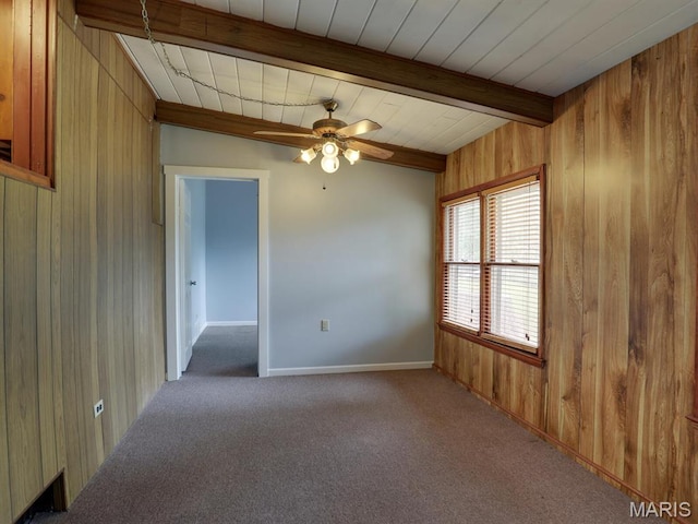 carpeted empty room with wood walls, beam ceiling, ceiling fan, and baseboards