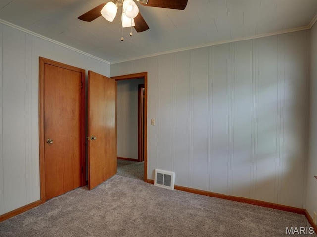 unfurnished bedroom featuring carpet floors, ornamental molding, and ceiling fan