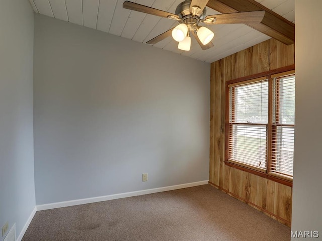 unfurnished room featuring wood walls, light carpet, baseboards, ceiling fan, and wooden ceiling