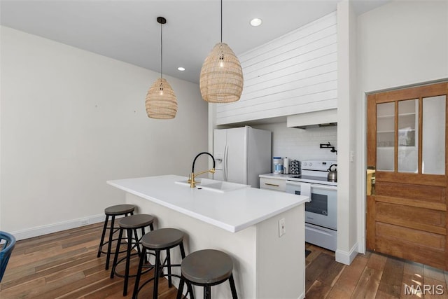 2765 Caroline St, Saint Louis, MO 63104 - kitchen with white appliances, dark wood-style flooring, recessed lighting, a breakfast bar, and backsplash