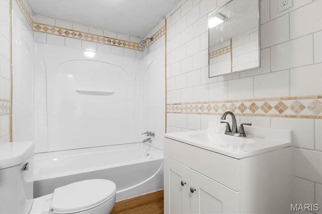 full bathroom with tile walls, toilet, shower / washtub combination, vanity, and wood finished floors