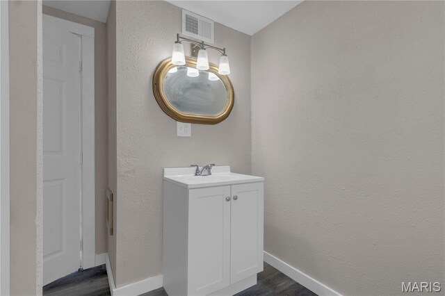 317 S Louisiana St, Cape Girardeau, MO 63703 - bathroom with wood finished floors, vanity, baseboards, and a textured wall
