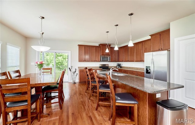 3 Lakeview Pointe Ct, Lake St Louis, MO 63367 - kitchen featuring stainless steel appliances, light wood-style floors, a sink, a kitchen breakfast bar, and brown cabinets