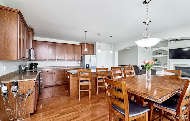 3 Lakeview Pointe Ct, Lake St Louis, MO 63367 - dining area with light wood-style flooring, arched walkways, built in shelves, a glass covered fireplace, and a ceiling fan