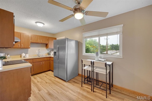 2794 Pinebrook Dr, Arnold, MO 63010 - kitchen featuring stainless steel refrigerator with ice dispenser, wall chimney range hood, light countertops, light wood finished floors, and a sink