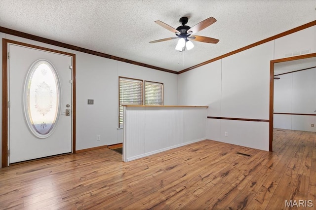 foyer entrance with a textured ceiling, plenty of natural light, ornamental molding, a ceiling fan, and wood-type flooring