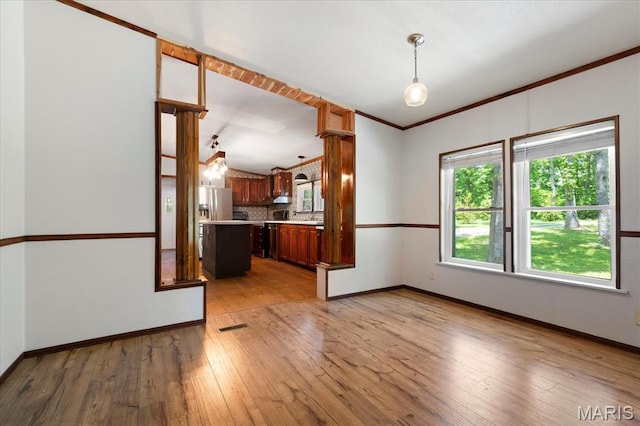 unfurnished living room with plenty of natural light, wood-type flooring, baseboards, and crown molding