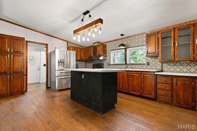 kitchen with stainless steel refrigerator with ice dispenser, crown molding, light countertops, hardwood / wood-style flooring, and decorative backsplash