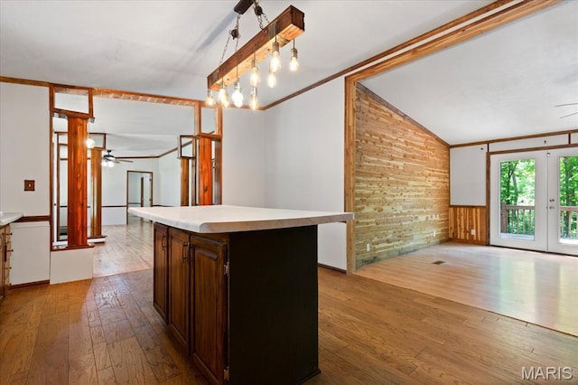 kitchen with hardwood / wood-style flooring, a ceiling fan, light countertops, wainscoting, and lofted ceiling