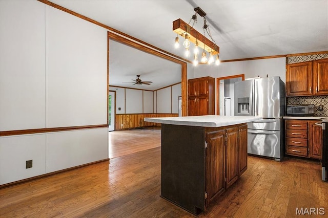 kitchen featuring stainless steel refrigerator with ice dispenser, light countertops, decorative backsplash, hardwood / wood-style floors, and a center island
