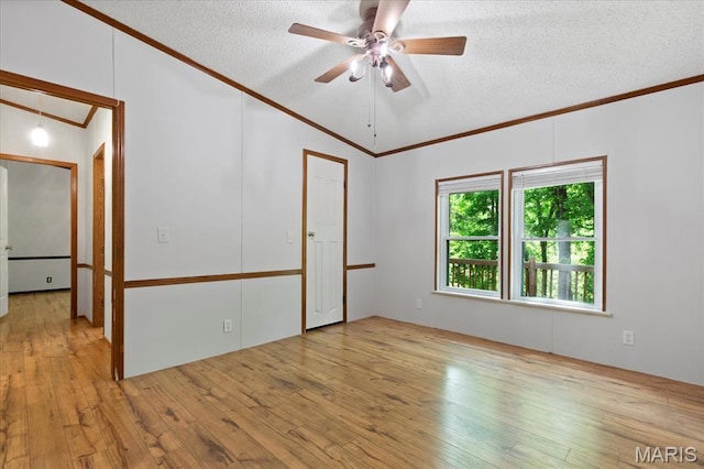empty room featuring ornamental molding, vaulted ceiling, a textured ceiling, hardwood / wood-style floors, and ceiling fan