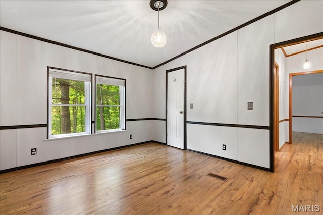 unfurnished room with ornamental molding, light wood-style flooring, and baseboards