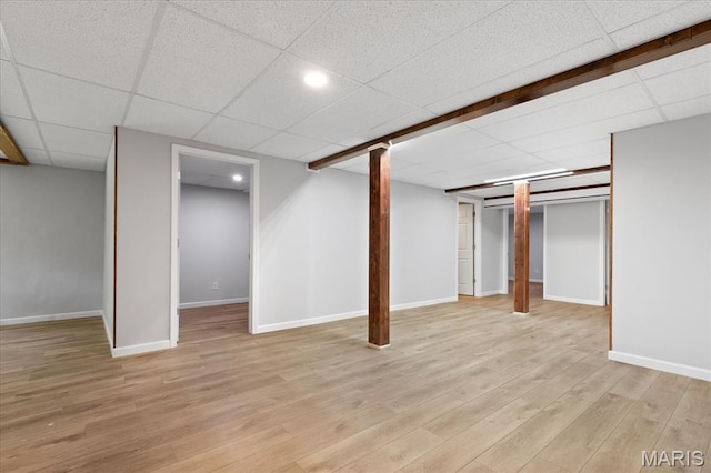 finished basement with light wood finished floors, baseboards, and a drop ceiling