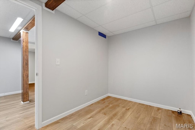 empty room with light wood-style floors, baseboards, and a drop ceiling